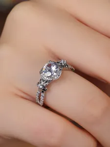 Detail of four-prong round diamond ring with floral lace band and micro-pave accents