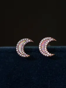 Macro shot of rose gold crescent moon stud earrings with opal and white crystals