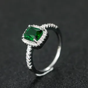 Macro shot of emerald cut green gemstone ring with silver halo setting and pavé side stones