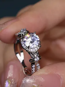 Macro shot of silver ring featuring a round halo crystal and floral side details