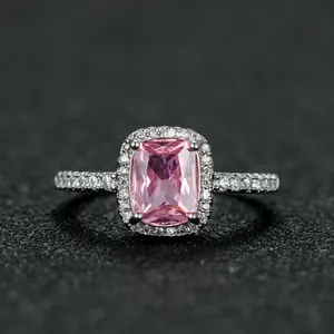 Macro shot of rectangular pink gemstone ring with white zircon halo and silver band