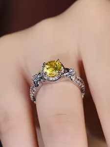 Macro shot of silver ring featuring a large round yellow gem with hollow carved details