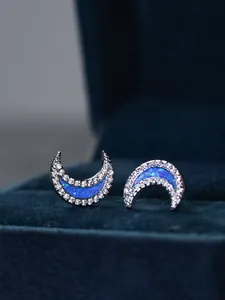 Macro view of crescent moon stud earrings with blue opal and white zircon inlay