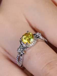 Macro detail of silver floral ring featuring a large yellow round diamond and butterfly accents