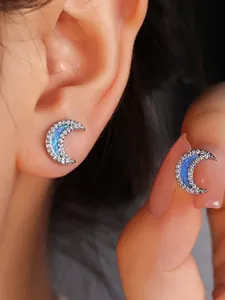 Detail shot of silver crescent moon earrings with blue opal and shimmering zircons