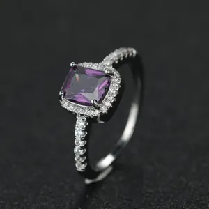 Macro shot of rectangular purple gemstone ring with sparkling diamond halo setting