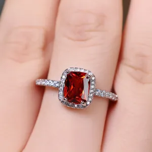 Macro shot of silver halo ring featuring a rectangular red gemstone and pavé diamonds
