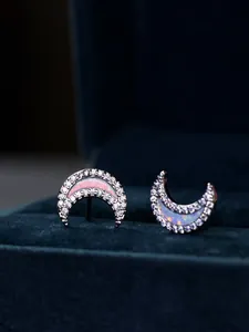 Detail of crescent moon studs with pink fire opal and pavé crystals on blue velvet