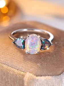 Macro detail of oval opal ring with rainbow heart accents on a velvet jewelry box