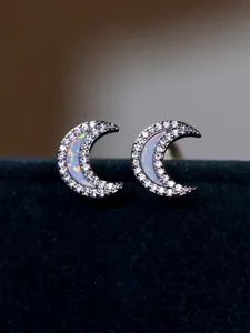 Close-up of crescent moon stud earrings with white opal and pavé cubic zirconia