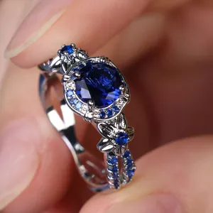 Elegant silver ring with a large round blue stone and intricate floral halo detail