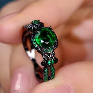 Gothic black metal ring with a large round green gemstone and floral engravings