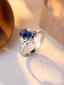 Dettaglio macro di anello in argento a corna con pietra blu scuro e diamanti bianchi
