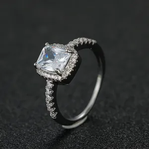 Macro view of rectangular cushion-cut diamond ring with silver halo setting on black background