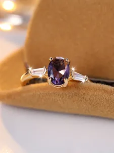 Macro di anello d'oro con gemma viola ovale e diamanti laterali a taglio baguette