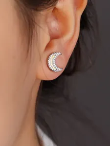Macro shot of silver crescent moon stud earring with opal inlay and sparkling zircons