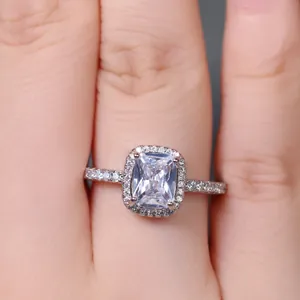 Macro shot of silver ring featuring a rectangular halo-set crystal on a model's finger
