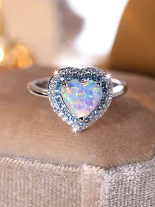 Gros plan d'une bague opale en forme de cœur avec double halo de cristaux