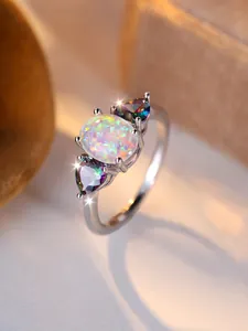 Detail of a silver ring featuring a white opal center and colorful heart-shaped side stones