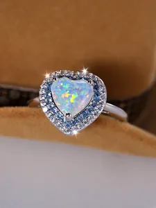 Vue macro de la bague en opale blanche en forme de cœur avec double halo de diamants