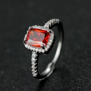 Elegant silver ring with rectangular red zircon and sparkling halo on black background