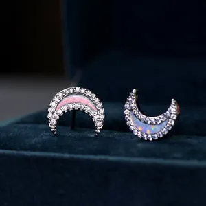 Crescent moon stud earrings with opal stone and white zircon on blue velvet