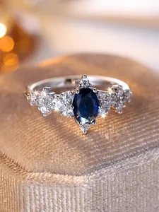 Primo piano di anello d'argento con grande pietra blu ovale e gemme bianche laterali