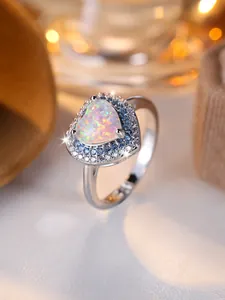 Gros plan d'une bague opale en cœur avec halo de diamants bleus et blancs