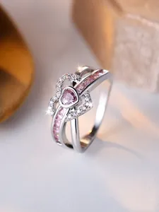 Detail of silver crossover ring featuring pink heart crystal and pavé set diamonds