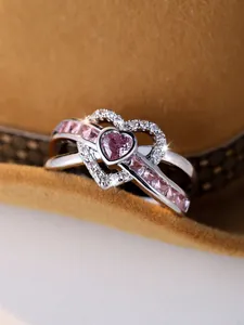 Macro shot of double heart ring with pink gemstones on a textured brown velvet fabric