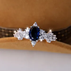 Anello d'argento con un grande zaffiro blu ovale e accenti di zircone sul lato