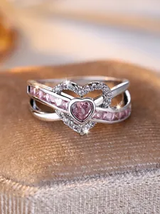 Macro view of double layer heart ring with pink gemstones and cross-over diamond band