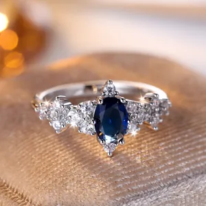 Elegante anello in argento con una gemma ovale blu e un alone di diamanti bianchi