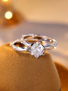Detailed view of silver wedding ring set with sparkling zircon on a brown velvet stand