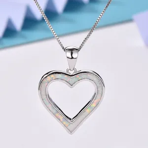 Close-up of heart-shaped blue opal pendant necklace with silver chain and white fire effect