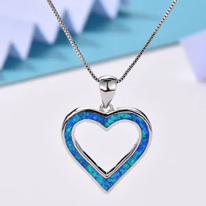 Macro detail of silver heart necklace featuring blue fire opal inlay on box chain