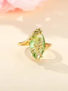 Macro detail of gold dragonfly ring featuring a large marquise cut green gemstone
