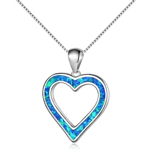 Macro detail of heart-shaped opal pendant with silver box chain on white background