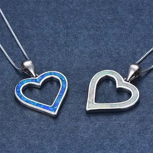 Close-up of heart-shaped blue opal pendants on silver chains with matte blue background