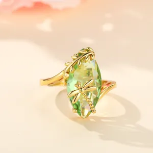 Golden dragonfly ring featuring a large marquise-cut emerald green gemstone and leaf detail