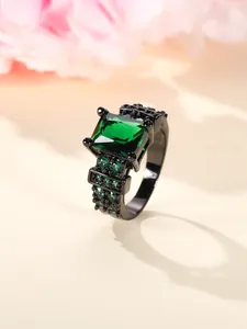Detail of square green gemstone ring with pavé side stones on black metal band