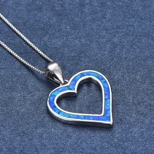 Macro detail of heart-shaped hollow pendant with blue opal inlay and silver box chain