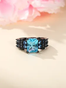Macro view of blue zircon ring featuring a rectangular stone and black plated metal band