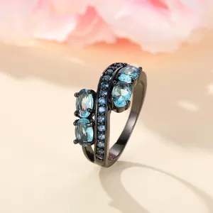 Macro detail of bypass ring with light blue oval stones and dark blue accents on black band