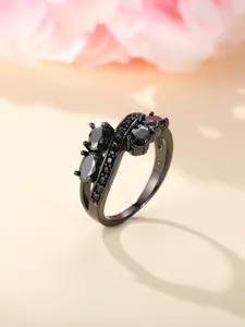 Detailed view of black metal wave ring with black zircons and oval gemstones