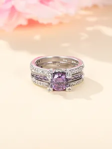 Detail van een driedelige zilveren ringenset met een grote ronde paarse edelsteen in zetting