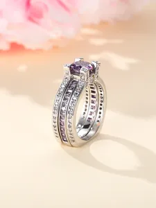 Macro-detail van zilveren ring met grote paarse middensteen en pavé gezette zij-diamanten