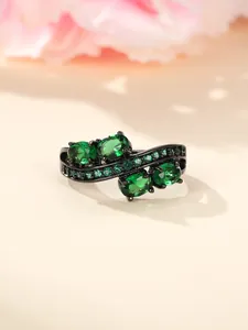 Macro shot of irregular ring with green gemstones and black nickel plating detail