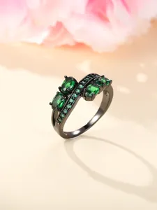 Detailed macro view of black plated irregular ring with emerald green oval gemstones
