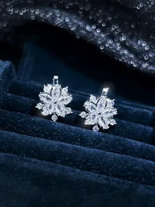 Macro shot of silver snowflake earrings with clear zircons on dark blue velvet